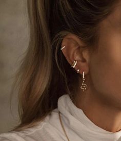 a close up of a person wearing gold earring and white turtle neck shirt with the word love written on it