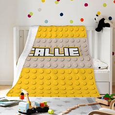 a child's bedroom with lego themed bedding and toys on the floor in front of it