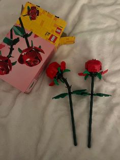 two red roses are in front of a lego box