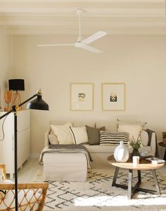 a living room filled with furniture and a white ceiling fan in the middle of it