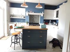 a dog laying on the floor in a kitchen next to an island with stools