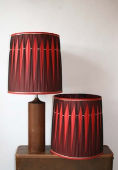 two red lamps sitting on top of a wooden table