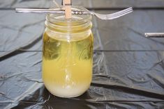 a glass jar filled with liquid sitting on top of a table next to a fork