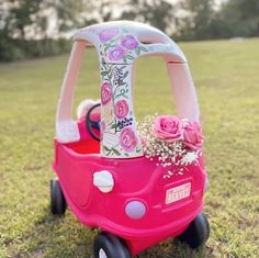 a pink toy car with flowers on the front and back wheels is sitting in the grass