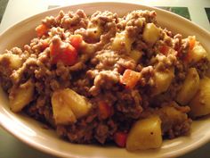 a white plate topped with meat and potatoes