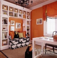 a living room with an orange wall and white bookcases filled with books on top of them