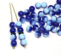 some blue beads are laying next to each other on a white surface with gold pins