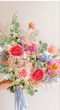 a person holding a large bouquet of flowers in their left hand and the other hand