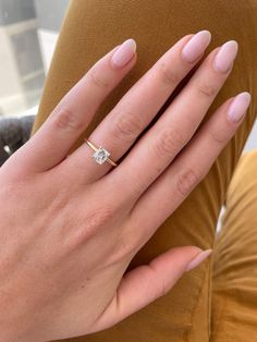 a woman's hand with a diamond ring on her left finger, sitting down