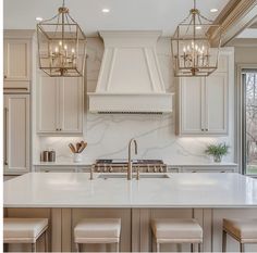 a kitchen with marble counter tops and gold pendant lights hanging from the ceiling over the island