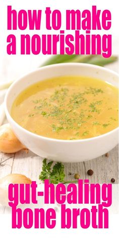 a white bowl filled with soup sitting on top of a wooden table next to garlic