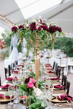 a long table is set with place settings and flowers in tall vases on each side