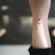 a small purple flower on the left side of the leg, with light shining through it