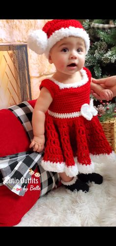 a baby wearing a red dress and santa hat