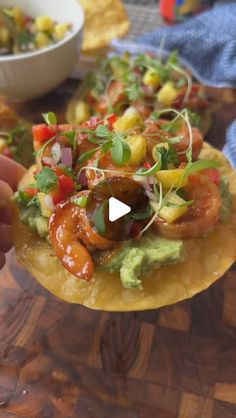 a person is holding up a tortilla with shrimp and avocado