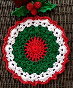 a crocheted christmas ornament on a wicker mat with holly leaves