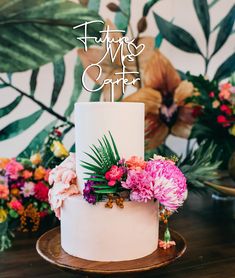 a white wedding cake with pink flowers and greenery