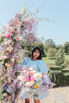 a woman standing in front of a flower arch