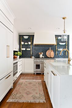 a kitchen with white cabinets and wood flooring next to a rug on the floor