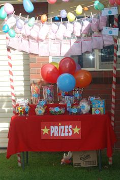 a table topped with candy and balloons in front of a building