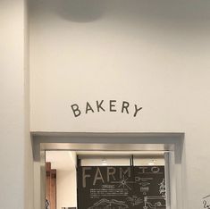 an open door to a bakery with writing on the wall and below it is a chalkboard drawing