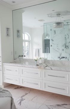 a white bathroom with marble counter tops and large mirrors on the wall over the sinks