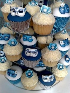 cupcakes with blue and white frosting are arranged in a tiered display