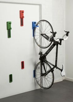 a bike mounted to the side of a white wall next to a blue and red hook