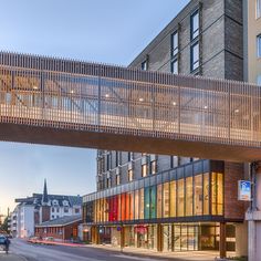 a pedestrian bridge over a city street next to tall buildings