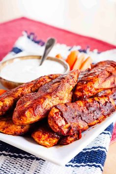 grilled chicken wings and carrots on a plate with ranch dip in the background