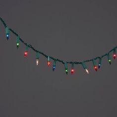 a string of christmas lights hanging from the side of a building in front of a dark sky