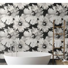 a white bath tub sitting next to a black and white flower wallpaper covered wall