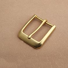 a gold square buckle on a beige background