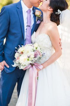 the bride and groom are kissing each other in their wedding day attire with pink ribbons