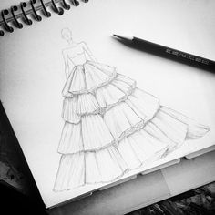 a drawing of a dress on paper next to a pen