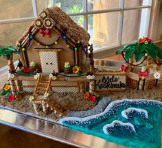 a gingerbread house decorated in the shape of a wave and beach scene with palm trees