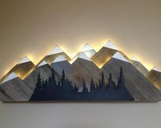 there is a painting on the wall that has mountains in it and lights above it