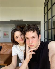 a young man and woman sitting next to each other in front of a glass door