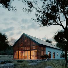 a house is lit up at night by the trees and grass in front of it