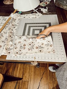 a person cutting fabric on top of a wooden table