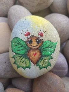 a painted rock with a lady bug on it's face and leaves around its body