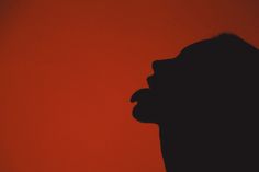 the silhouette of a person's head against an orange background