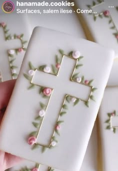 handmade cookies decorated with flowers and a cross on one piece of white icing