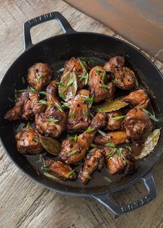 a skillet filled with meat and vegetables on top of a wooden table