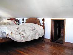 a bed sitting on top of a wooden floor in a bedroom