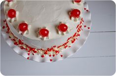 a cake with white frosting and red sprinkles