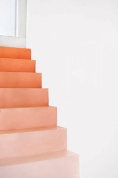 an orange stair case sitting on the side of a white wall next to a window