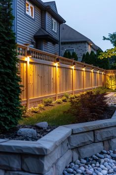 a fence that has lights on it and some rocks in the grass next to it