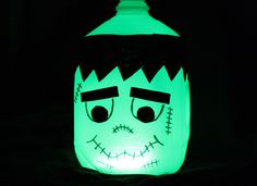 a lighted jar with a face on it in the dark, lit up for halloween