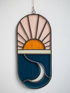 a stained glass sun and moon hanging on the wall in front of a white wall